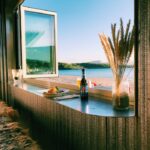 Enjoy a tranquil scene of a beach view in Norway through an open window with food and drink.
